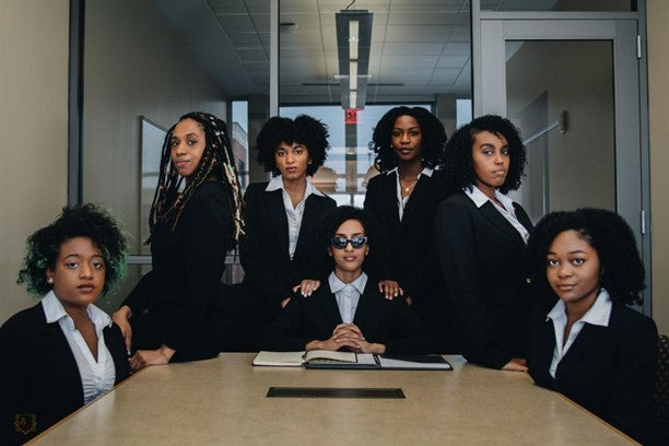 Women in suits and curly hair sitting in a business meeting 